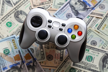 Silver wireless gamepad on dollar bills background