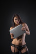 © Vitte Yevhen - Close up of Sexy young brunette woman in black sensual lingerie using laptop and posing on black background wall in studio.