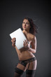 © Vitte Yevhen - Sexy young brunette woman in black sensual lingerie using laptop and posing on black background wall in studio.