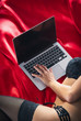 © Vitte Yevhen - Close up of Sexy young brunette woman in black sensual lingerie and in stockings using laptop on red bed in studio.