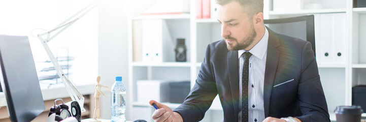 Wall Mural - A man sits at the office at the table and clicks a pen.