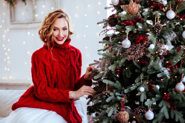 holidays, celebration and people concept - smiling woman in red sweater over christmas tree backgrou