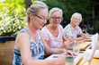 Retired senior women painting together outdoors as group recreational and creative activity during summer.