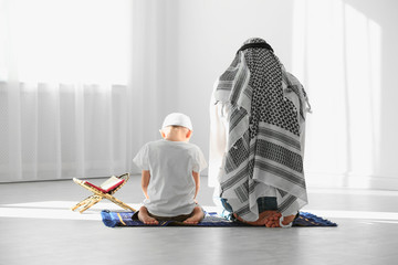 Wall Mural - Muslim man and his son praying together indoors