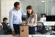 © fizkes - Colleague businessman supporting dismissal upset woman pack belongings in cardboard box, preparing to leave office, sad female office worker despair, feeling stressed about job loss, last day at work