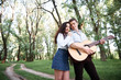© soleg - young couple walking in the forest and playing guitar, summer nature, bright sunlight, shadows and green leaves, romantic feelings