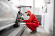 © rh2010 - Handsome auto mechanic in red uniform fixing disk for wheel alignment at the car service
