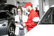 © rh2010 - Young woman client with auto mechanic in red uniform standing with some documents at the car service