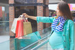 Beautiful pregnant woman with paper packages in the mall