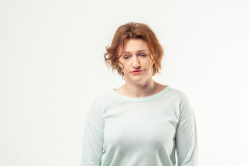 Beautiful red haired adult woman in casual looking down with tired sad expression on her face, upset, thinking about something, getting older on white background