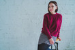 © Anton Dios - The girl in the red sweater and skirt. Brunette posing at a brick wall. Beautiful woman on grey background.