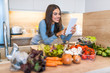 © Dragana Gordic - Smiling Young Woman Using Digital Tablet With Vegetable On Countertop In Kitchen