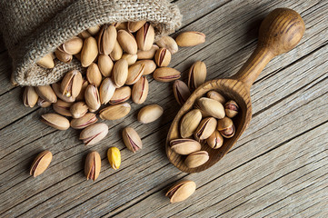 Wall Mural - Pistachio in nutshell on wooden rustic backdrop in wooden shovel, composition of Top view pistachios great for healthy and dietary nutrition. Concept of nuts