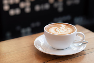 coffee latte in a white cup on wooden table in coffee shop.