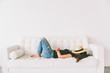 © CM Photo - A beautiful young woman relaxing on a white couch with a hat covering her face.