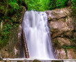 spring nature background. springtime scenery, wilderness landscape wallpaper with waterfall, cascade on long exposure, rocks and green vegetation in spring. outdoors, beauty in nature. 