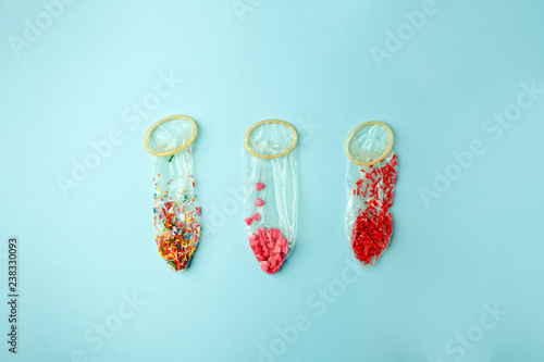 Fotografía Condoms filled with multicolored confetti and confectionary dressing on a pink b