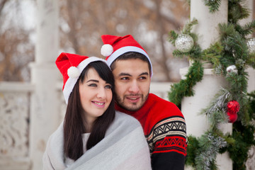 Beautiful young couple of lovers on a walk in the winter in anticipation of Christmas. Christmas decoration gazebo for a date