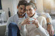 © goodluz - Attractive modern couple relaxing at home looking at camera