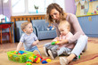 © Oksana Kuzmina - Mentor and 1 years old babies playing with educational toys in kindergarten or daycare centre
