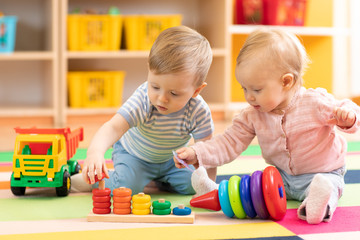 preschool boy and girl playing on floor with educational toys. children toddlers at home or daycare.