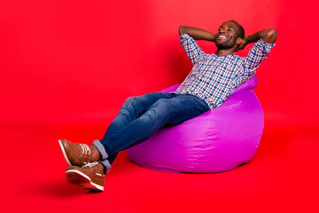 Wall Mural - Nice handsome cheerful positive guy wearing checkered shirt sitting on violet purple bag chill out isolated over bright vivid shine red background