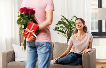 Poster - couple, relationships and people concept - happy woman looking at man with flowers and gift at home