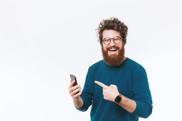 Wall Mural - Cheerful handsome bearded man poinitng at smart phone