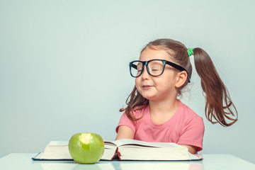 Wall Mural - beautiful cute little girl with happy expression next to book and green apple