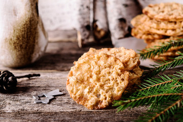 Wall Mural - Havreflarn - scandinavian crispy slim oatmeal cookies, fir and birch branches and bark on old wooden background. Fast and easy scandinavian pastry. Cozy winter treat. Hygge. Fika. Christmas