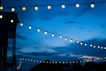 Row Of Hanging Summer Terrace Lights During Evening, Small Outdoor Light Bulbs.