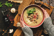 © Yulia - Bowl of mushroom cream soup in woman hands in a woolen sweater. Rustic dark background, top view, flat lay. Winter warming soup on vintage cutting boards.