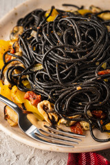 Wall Mural - Black pasta with seafood, anchovies, tomatoes and bell peppers.