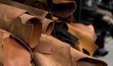 Different pieces of leather in a rolls. The pieces of the colored leathers. Rolls of natural brown red leather. Raw materials for manufacture of bags, shoes, clothing and accessories.