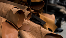 Different Pieces Of Leather In A Rolls. The Pieces Of The Colored Leathers. Rolls Of Natural Brown Red Leather. Raw Materials For Manufacture Of Bags, Shoes, Clothing And Accessories.