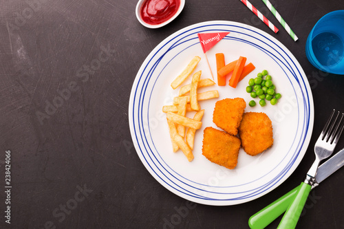 Fototapeta na szkło Posiłek dla dzieci (obiad) - nuggetsy z kurczaka, frytki i zielony groszek