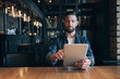 © nazarovsergey - Modern hipster businessman drinking coffee in the city cafe during lunch time and working on tablet