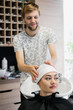 © romankosolapov - Close up of a young happy beautiful woman smiling to the camera while professional hairdresser wrapping her wet hair in a towel after washing it with shampoo