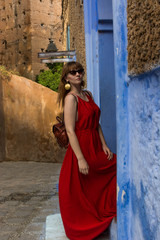 Wall Mural - Beautiful young brunette with bright make up, in a red ceremony dress. The blue pearl of Morocco, chefchaouen.