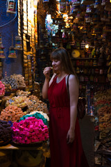 Wall Mural - Girl smelling handmade soap in Chefchauen, Morocco. Model traveling in red dress. Coasy shop in Africa.