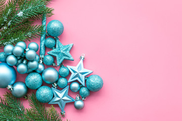 New Year and Christmas atmosphere. Decorate festive christmas tree. Christmas tree decoration. Colorful balls and stars near spruce branch, pine fir on pink background top view space for text