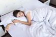 © dianagrytsku - Young woman sleeping under duvet in a white bed. top view