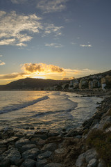 Sticker - View from a rocky beach of a coastal city at sunset in winter, Alassio, Liguria, Italy