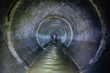 Diggers (urban explorers) are exploring underground river flowing in round sewer tunnel