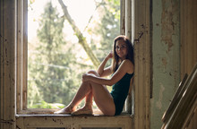 Portrait Of Ballet Dancer Sitting On Window Sill In Old Building