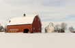 Beautiful winter farm scene with a bright red barn and white corn crib in a snowy field. Barn has a cupola and lightning rods. Concepts of farming, rural life, holidays