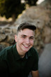 © Cavan Images - Close-up portrait of happy handsome man sitting against rock formations at park