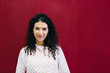 © Cavan Images - Portrait of confident businesswoman standing by red wall in creative office