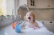 © Cavan Images - Shirtless girl drinking water from faucet in sink at home