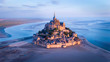 © Cavan Images - Aerial view of Mont Saint-Michel by river against sky during sunset